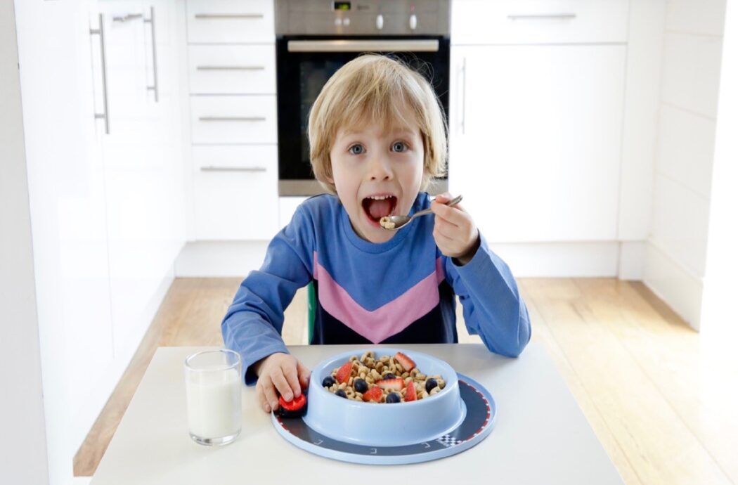 Child eating from Munchy Play plate with in-built toy.